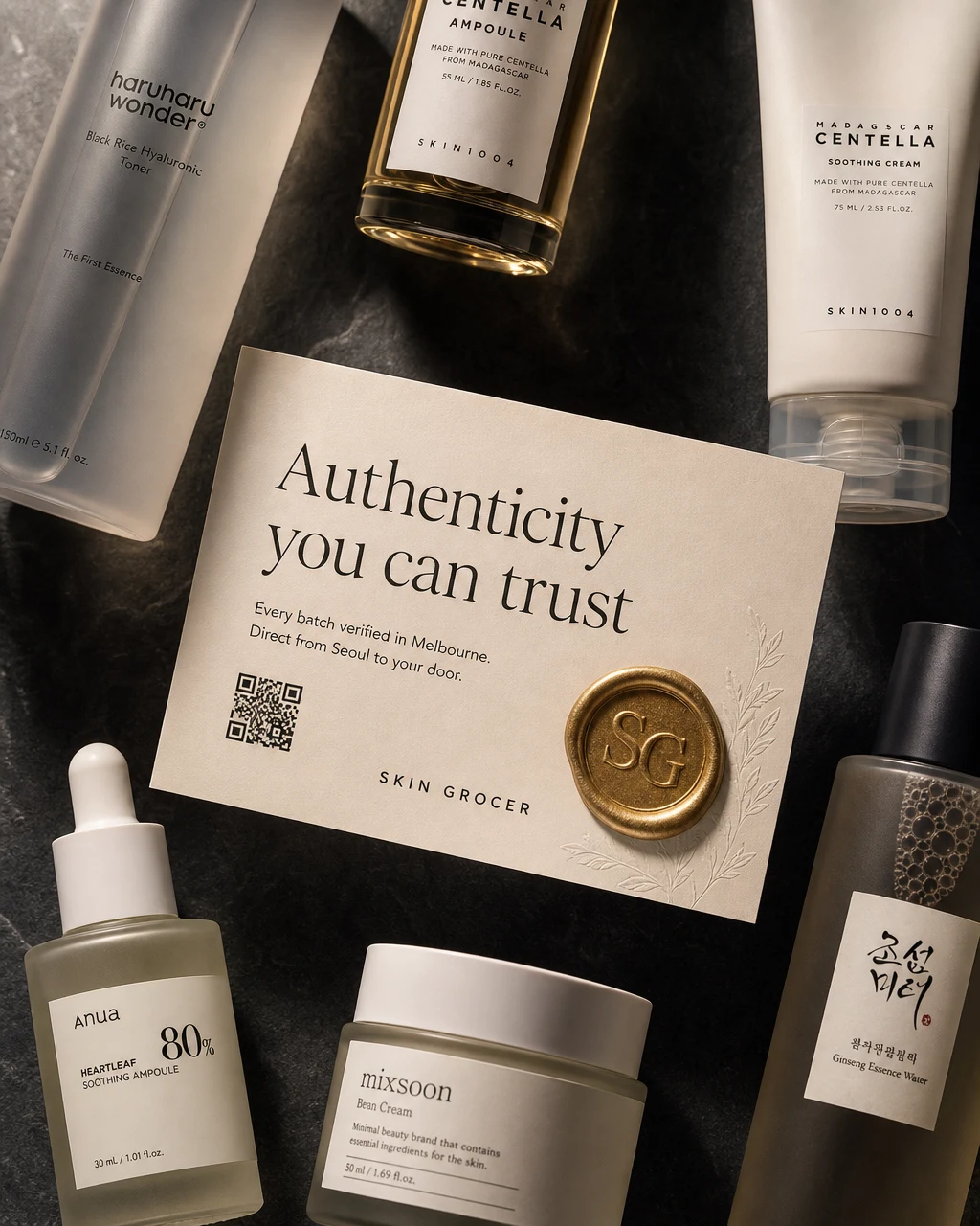 A Skin Grocer authenticity card with a wax seal, resting among Korean skincare in original branded packaging from Haruharu Wonder, SKIN1004, Anua, mixsoon and Beauty of Joseon