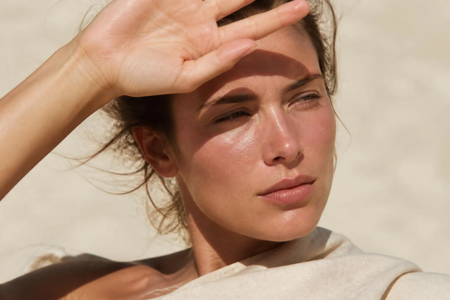 Woman shielding her face from harsh Australian sun, skin flushed and dry in bright daylight