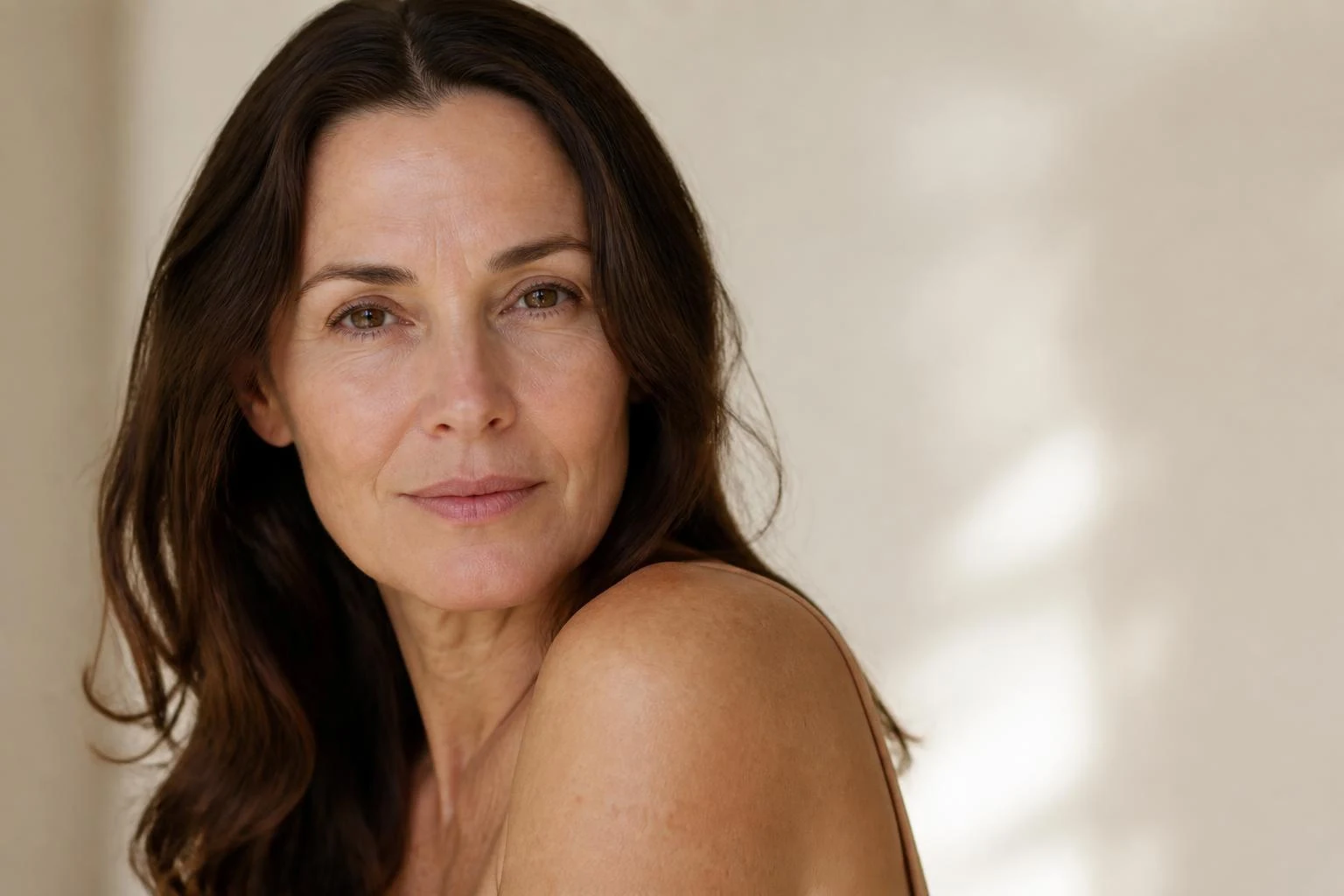 Portrait of a woman in her forties with bare, healthy skin and natural texture in soft daylight
